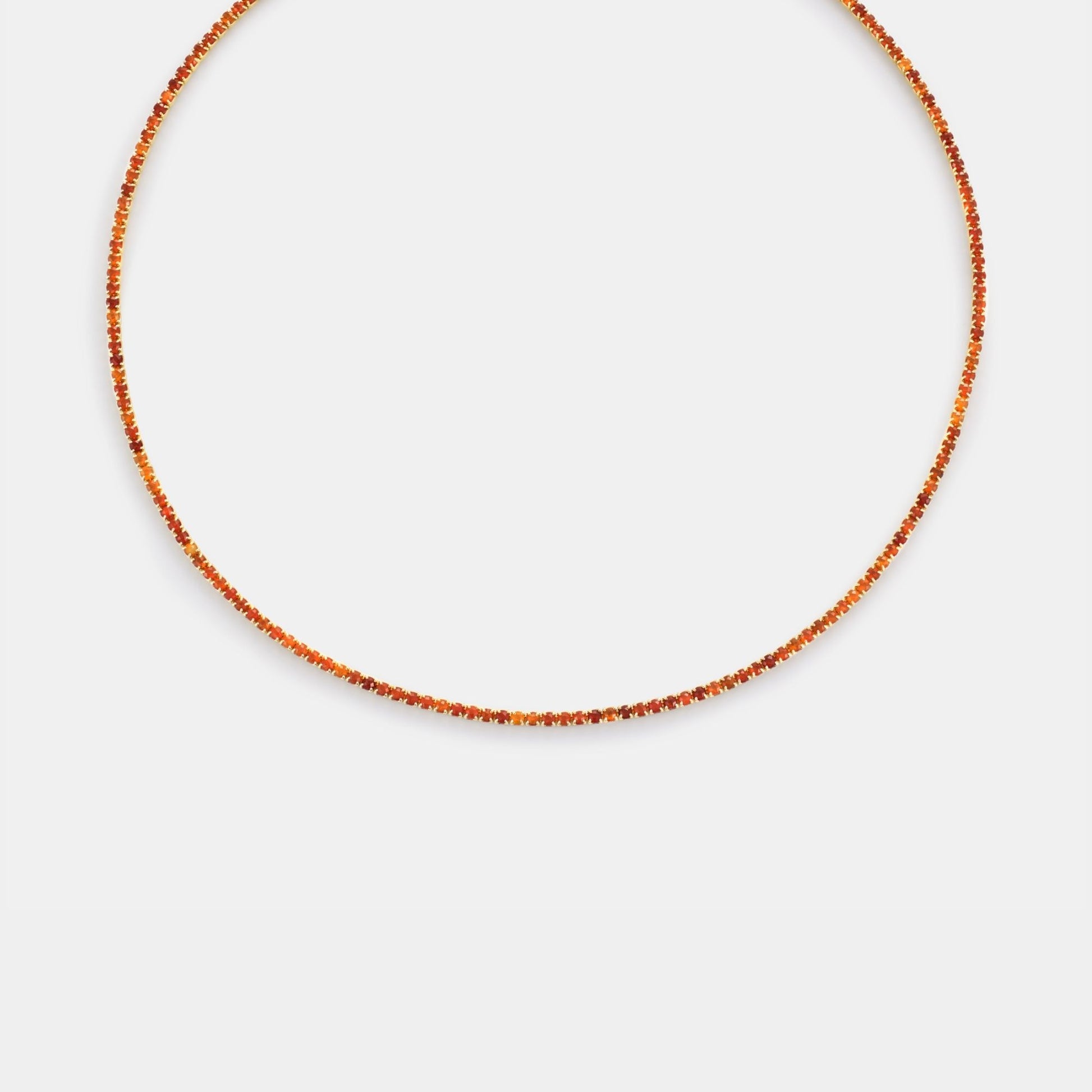Thin orange beaded necklace on a light gray background