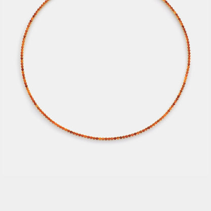 Thin orange beaded necklace on a light gray background