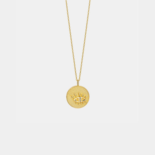 Gold necklace with a round pendant on a light gray background