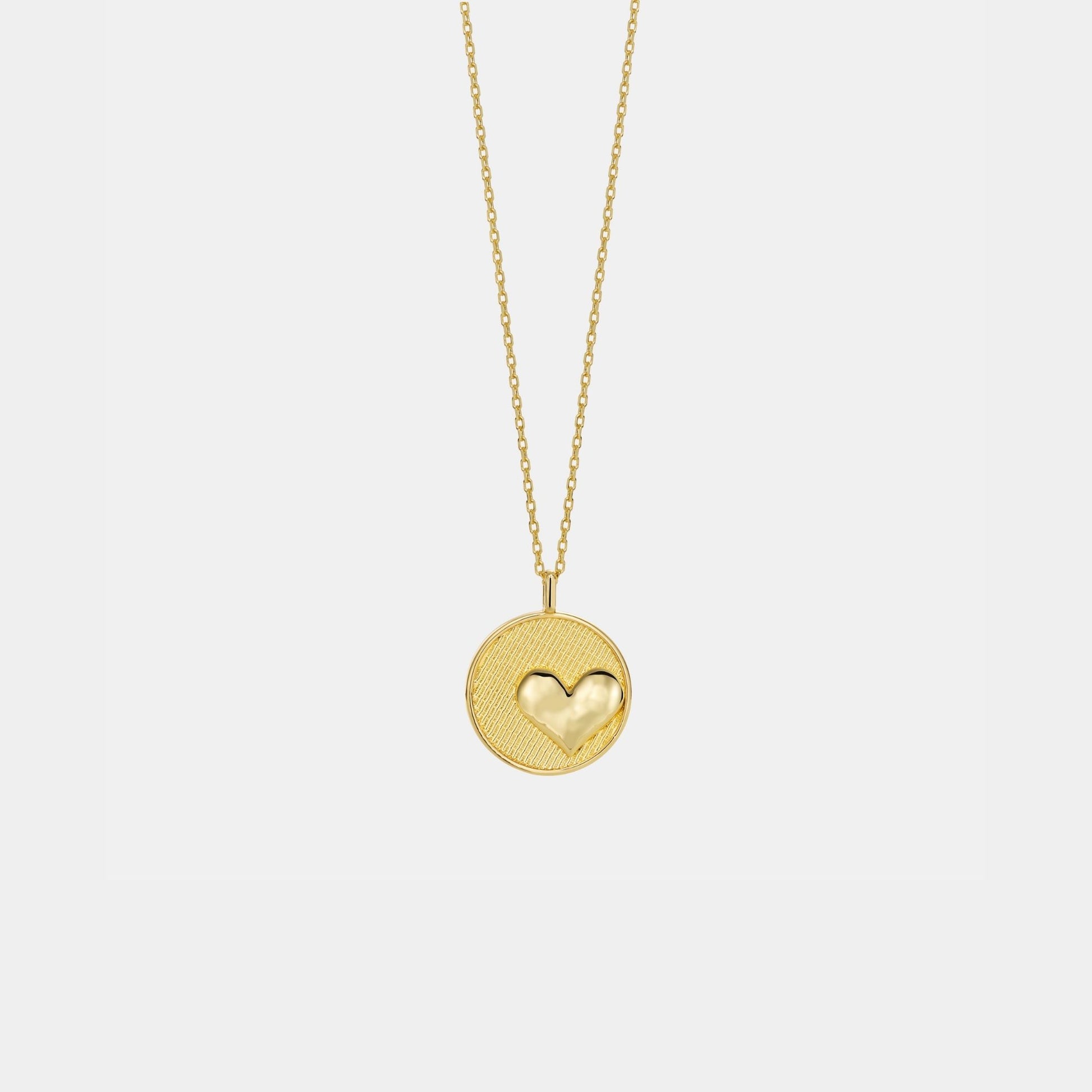 Gold necklace with a heart-shaped pendant on a light gray background